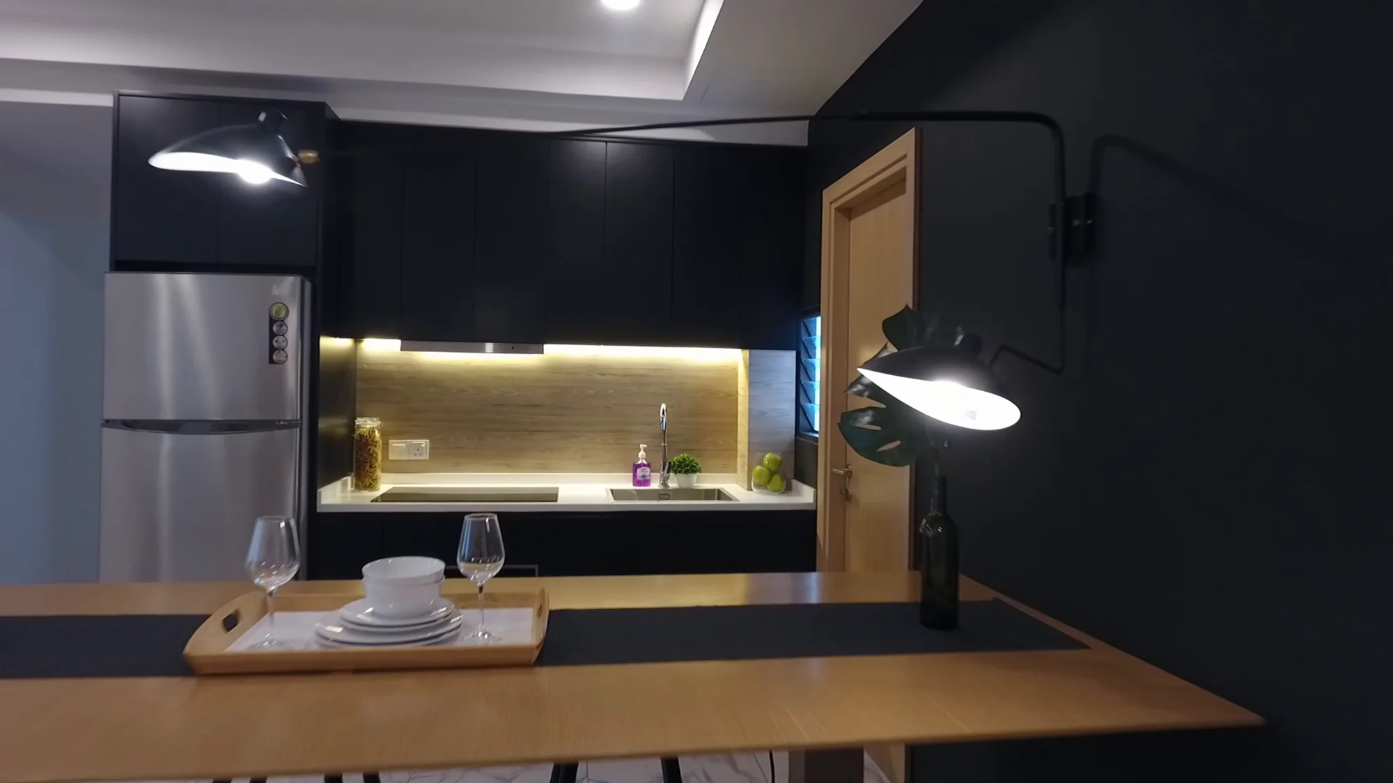 Dark-panel kitchen with lit counter and dining table set for two