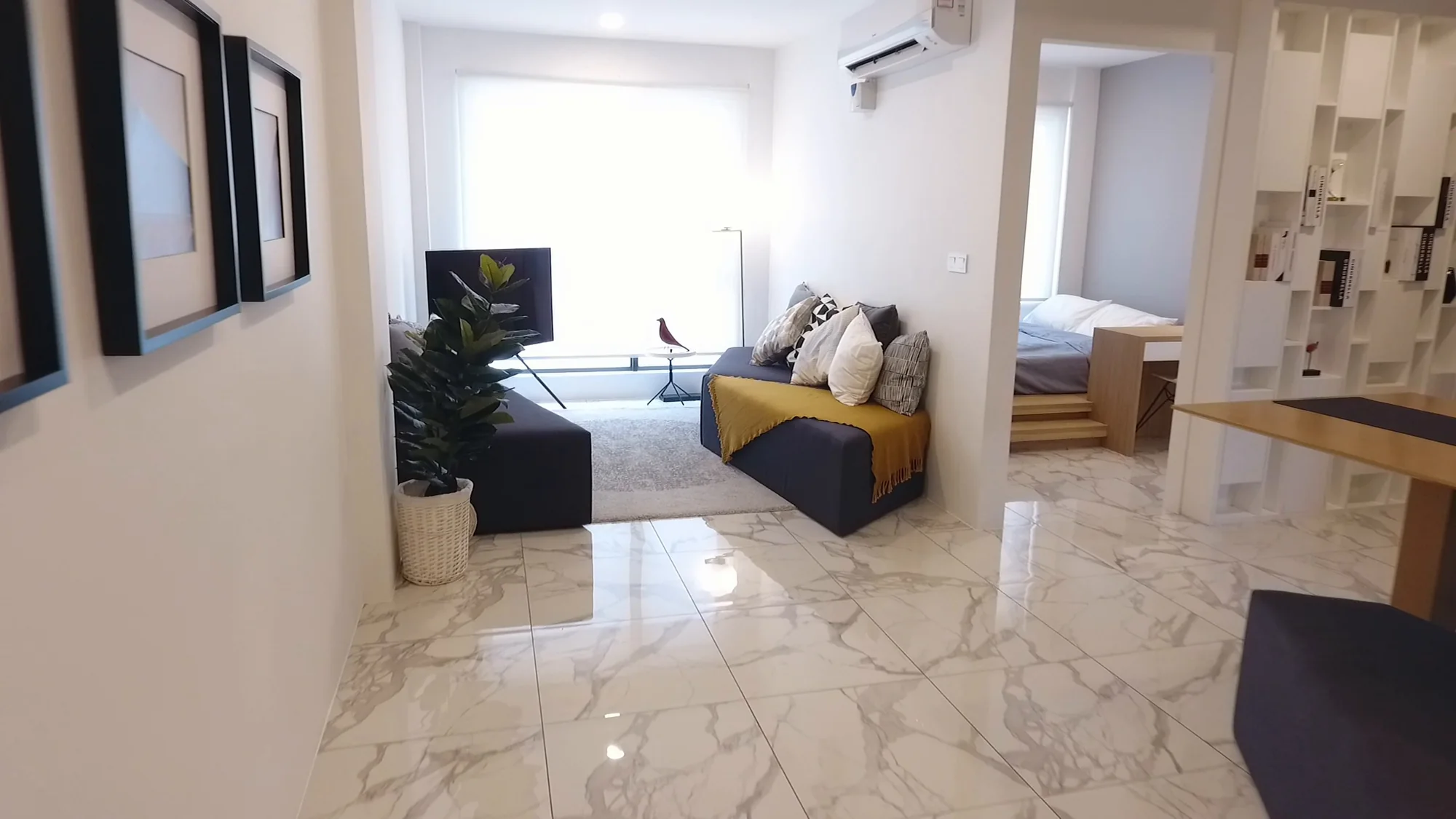 Show unit living area with marble floor, sofa and bedroom beyond