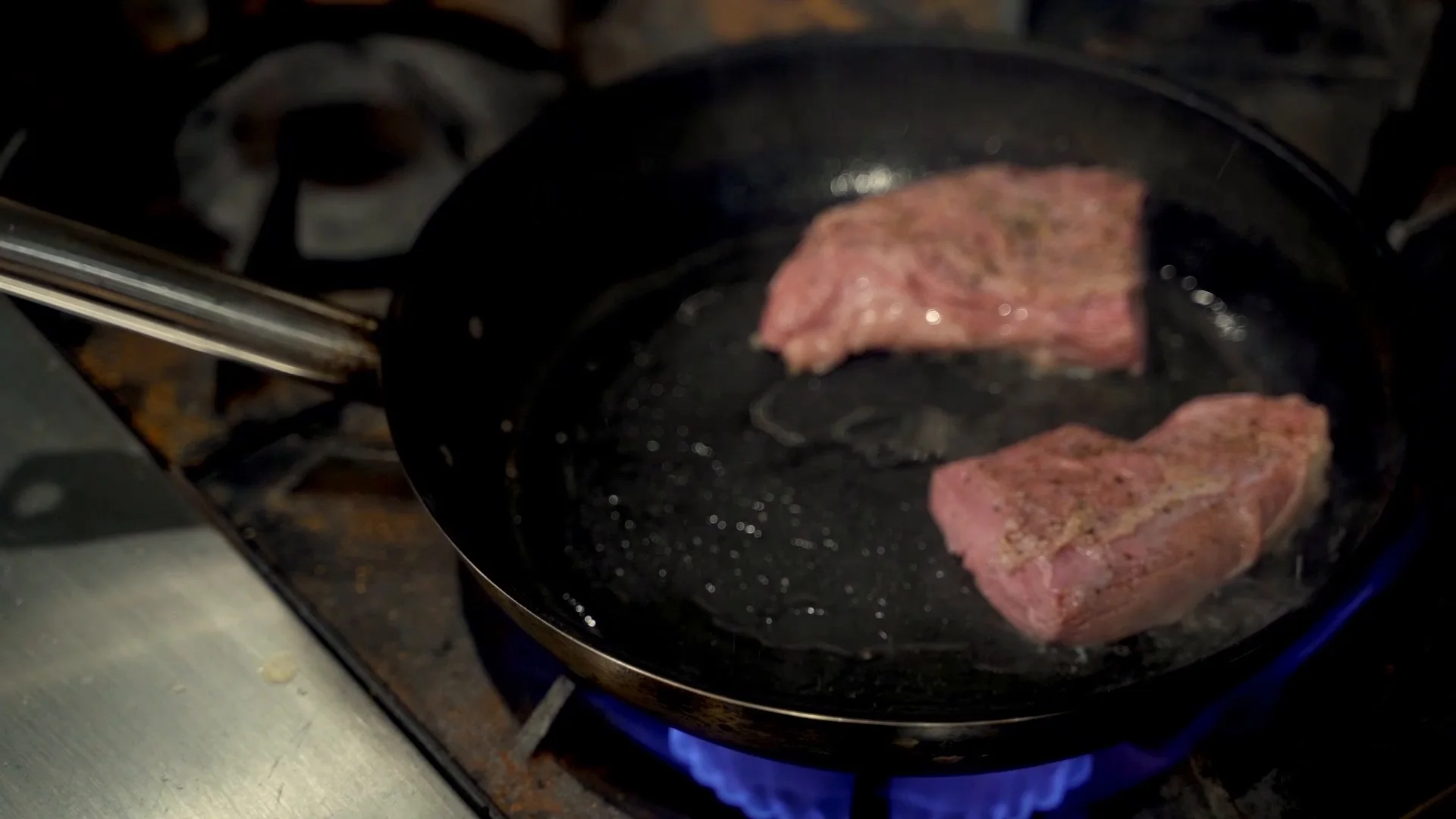 Wagyu beef searing in a pan over a blue flame