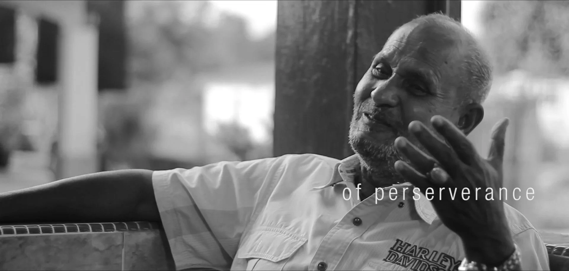 Black-and-white film still of a senior PESB figure laughing during an interview
