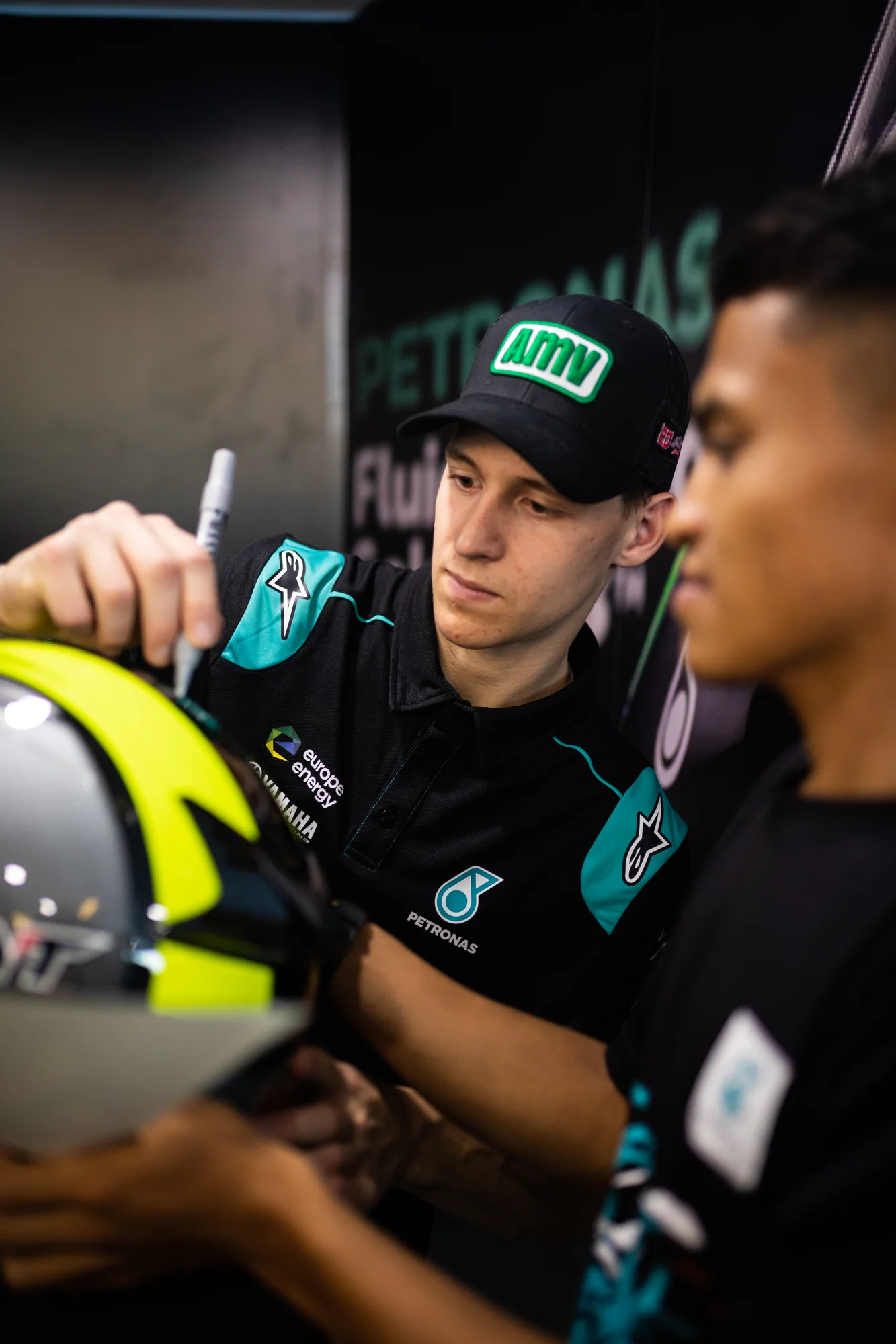 Petronas rider signing a helmet for a fan