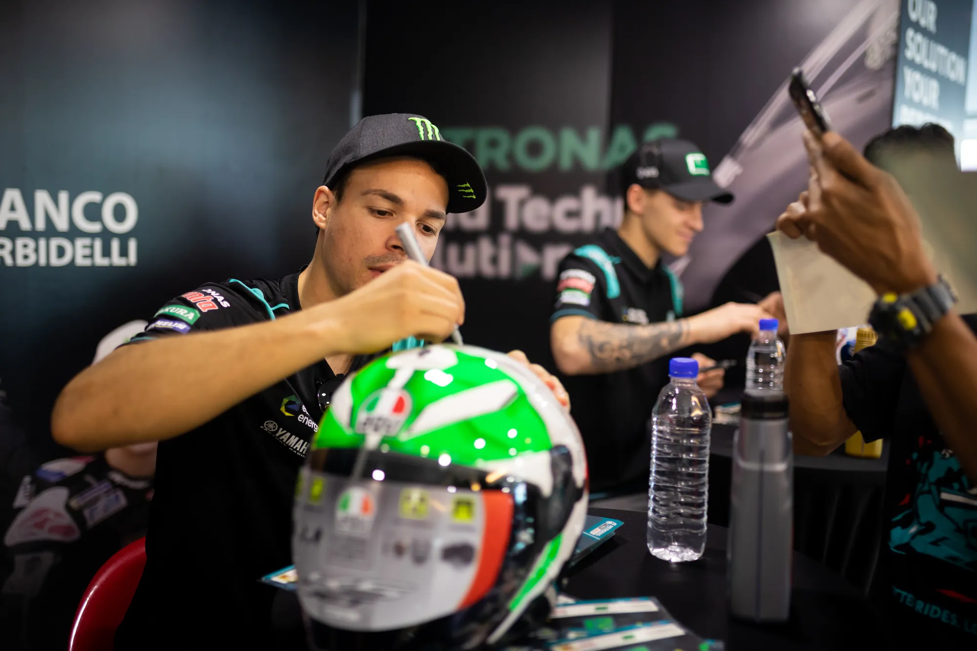 Rider signing a green helmet for a fan